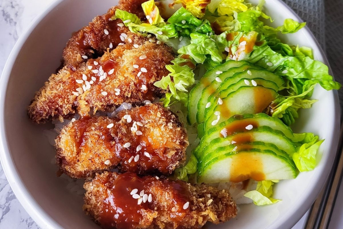 A bowl of asian chicken wings with salad and sesame seeds, perfect for a nourishing winter dinner.