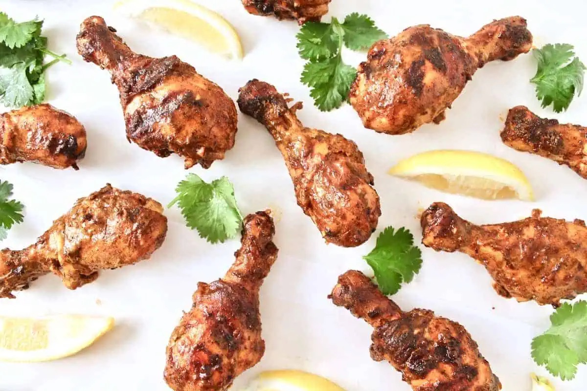 Chicken tikka masala skewers on a white plate with lemon wedges, perfect for a winter dinner.