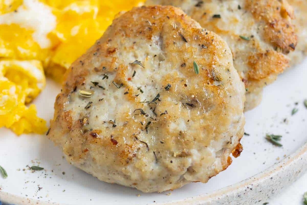 High protein chicken sausage patties and eggs with a dollop of healthy sour cream on a plate. Perfect for nutritious breakfasts.