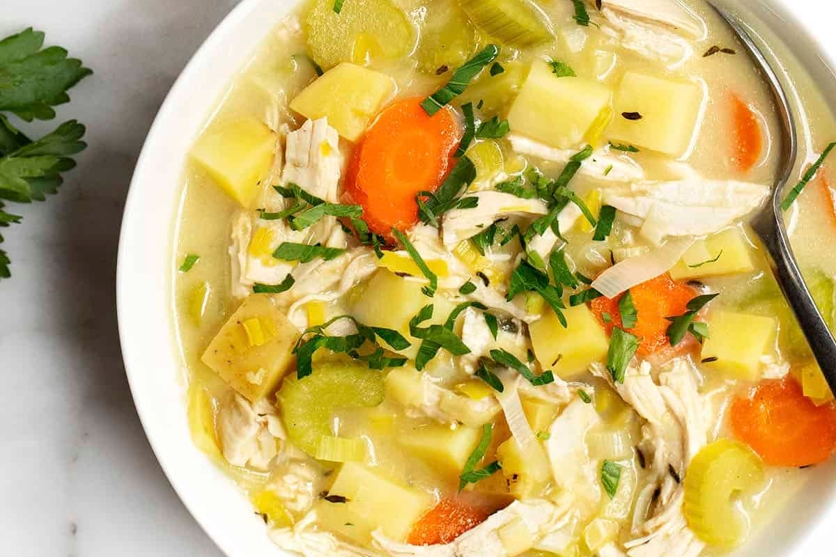 Potato soup in a white bowl with carrots and potatoes.