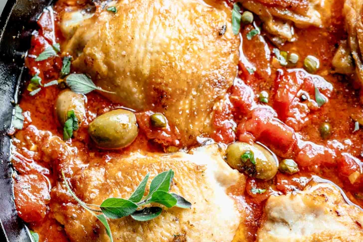 Chicken thighs cooked in a delicious tomato sauce in a skillet.