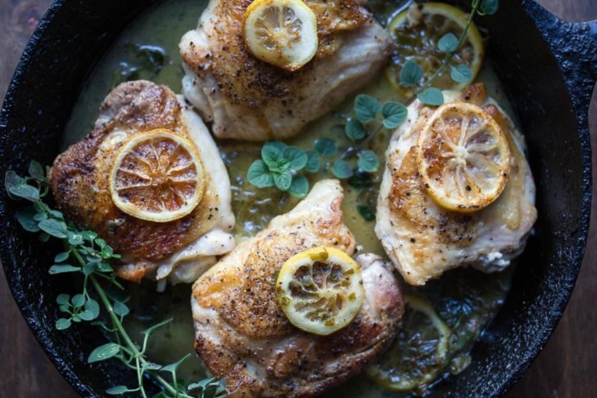 Lemon and thyme-marinated chicken thighs seared in a cast iron skillet.
