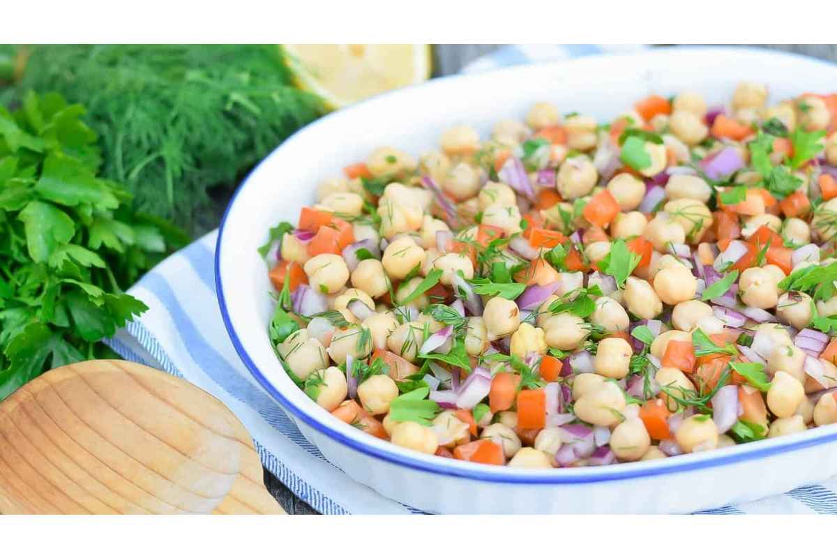 High protein chickpea salad in a white bowl with a wooden spoon.