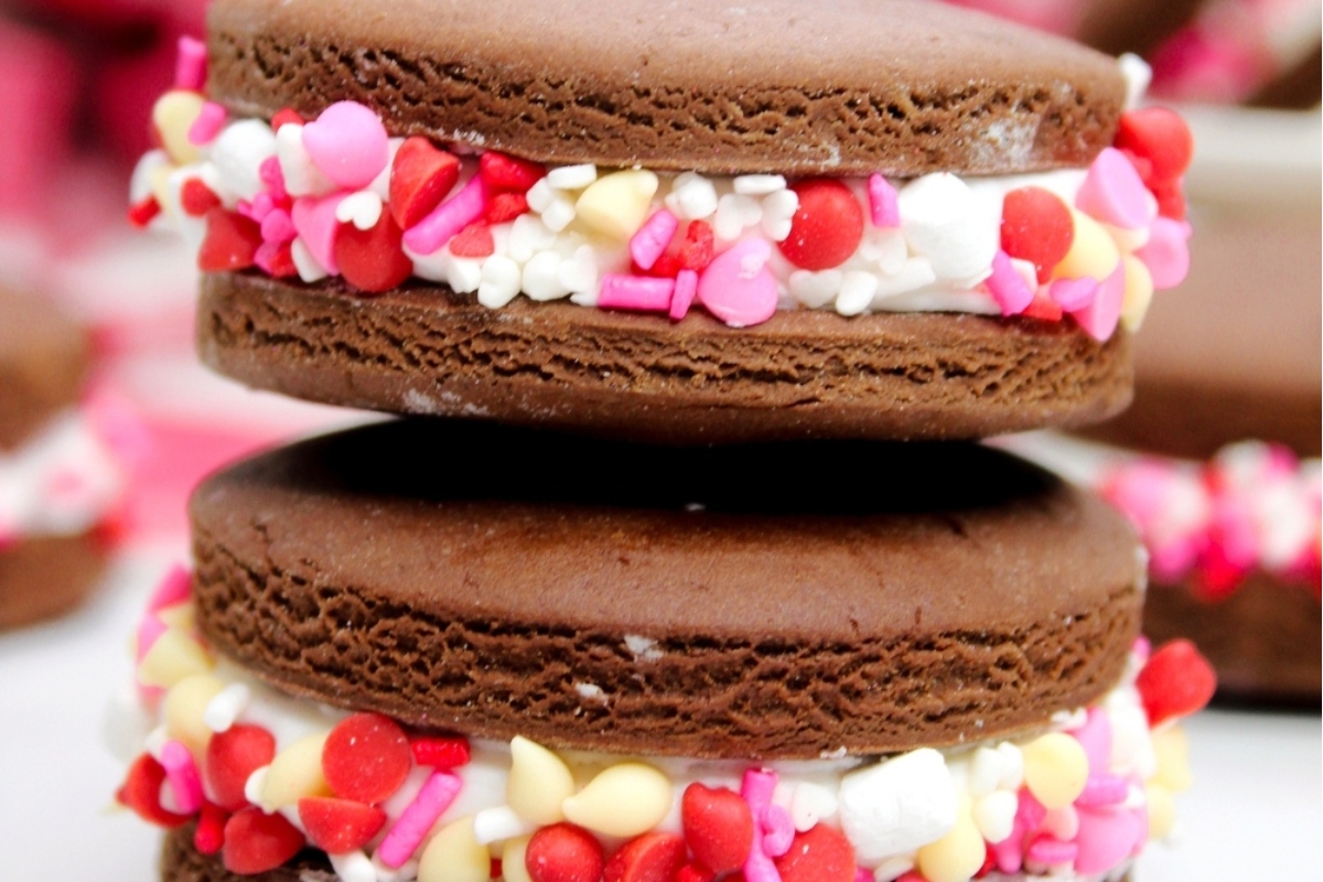 A stack of Valentine's Day themed chocolate oreos with sprinkles on top.