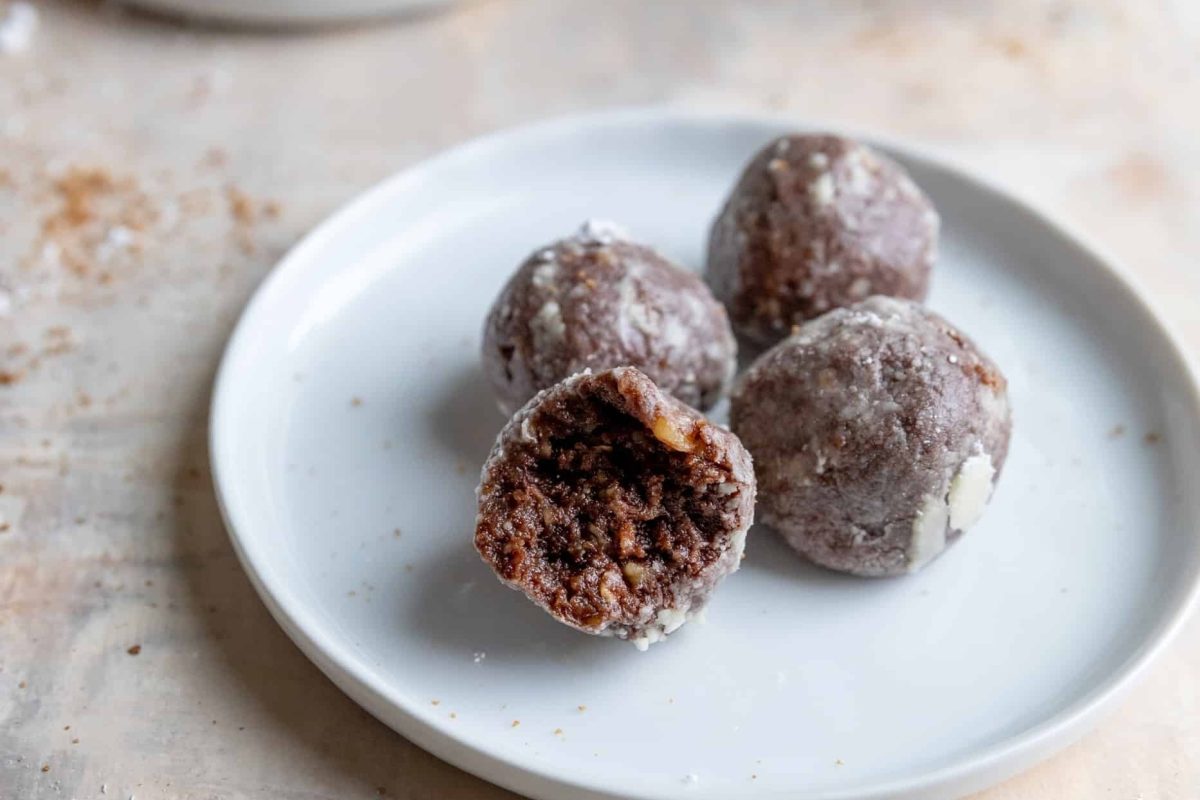 Chocolate protein balls on a plate with a bite taken out.
