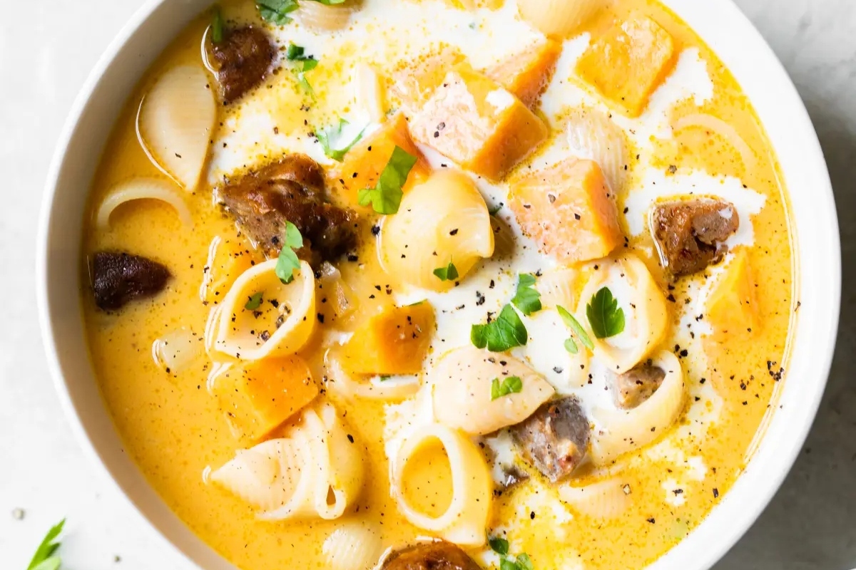 A bowl of potato soup with noodles and meat in it.