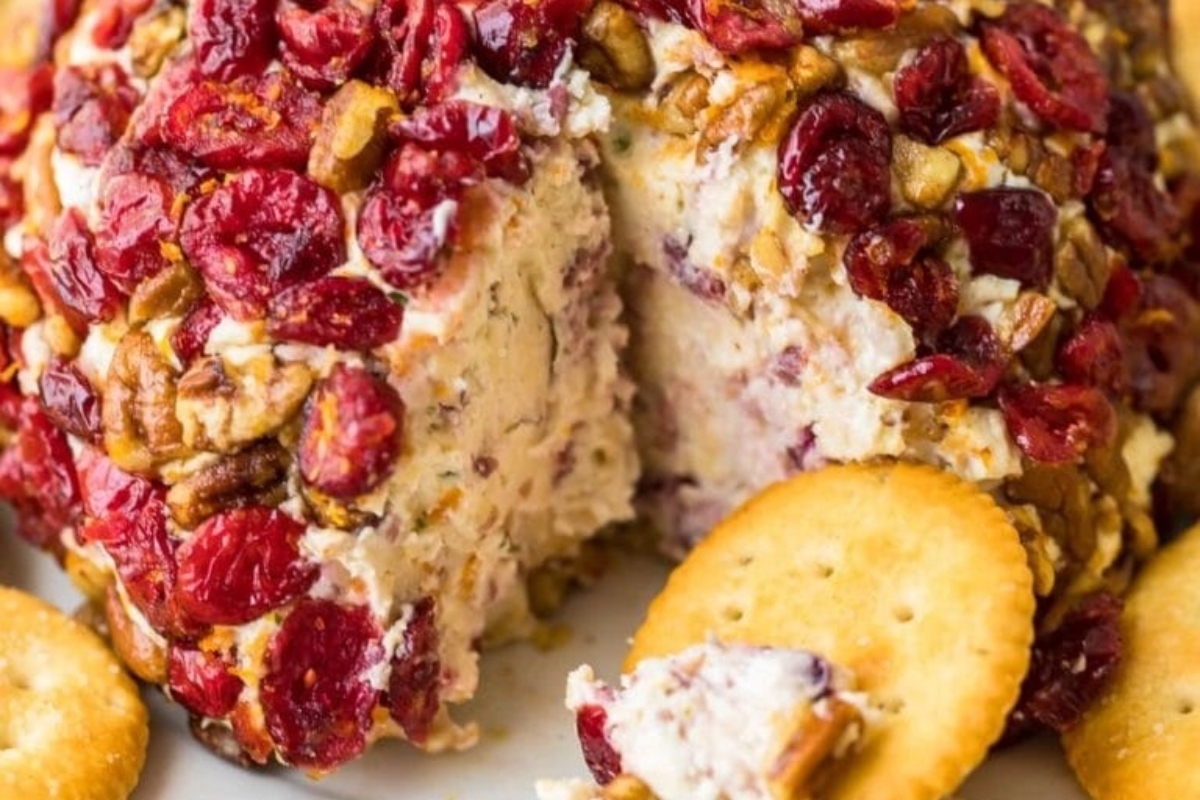 Festive cranberry cheese ball served with crackers on a plate.