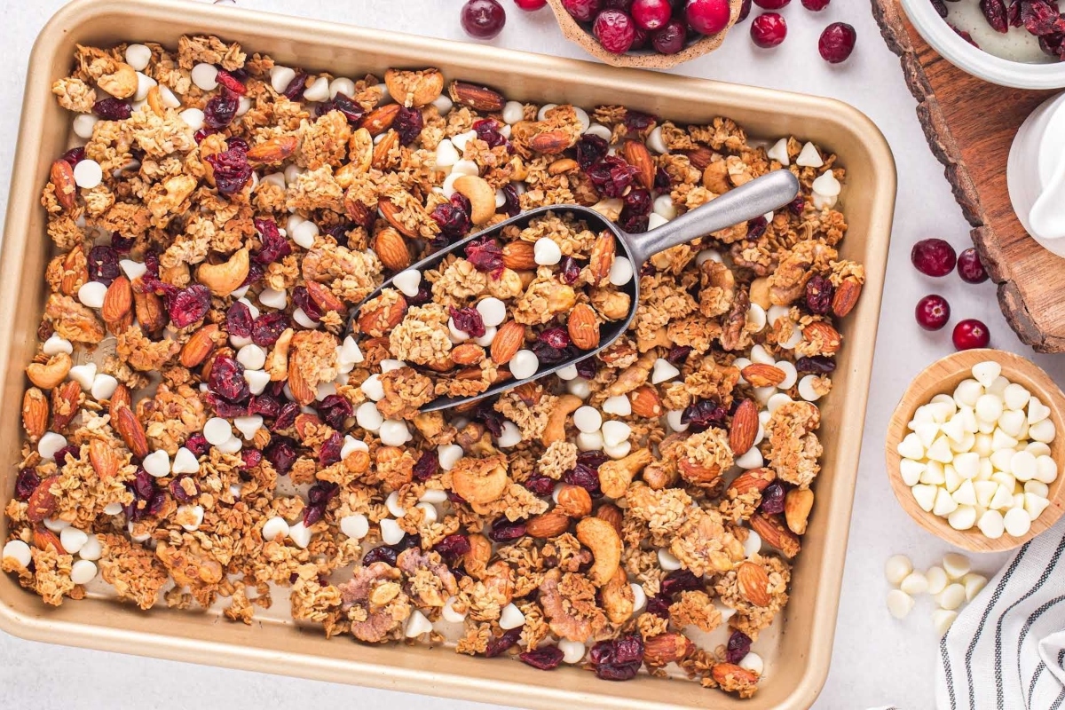 Cranberry granola, a delicious and healthy snack option, is beautifully presented in a baking pan with an assortment of nuts and cranberries.