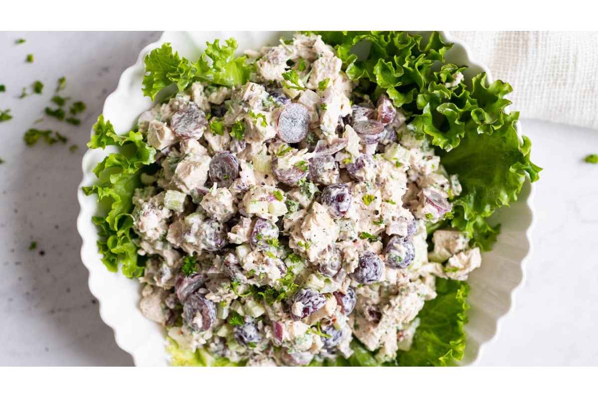 High protein chicken salad with grapes and lettuce in a white bowl, making it a healthy and filling option for lunches.