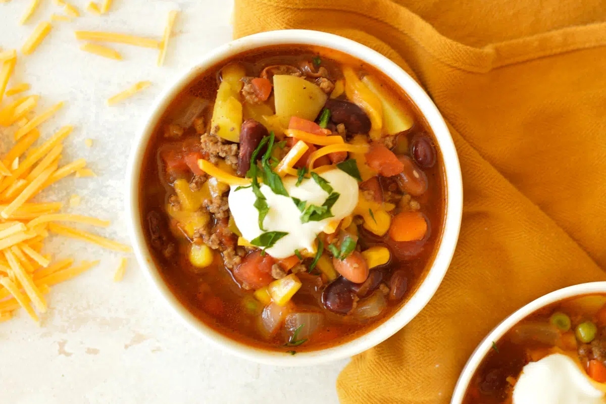 A mouthwatering recipe for chili, topped with generous amounts of cheese and sour cream.