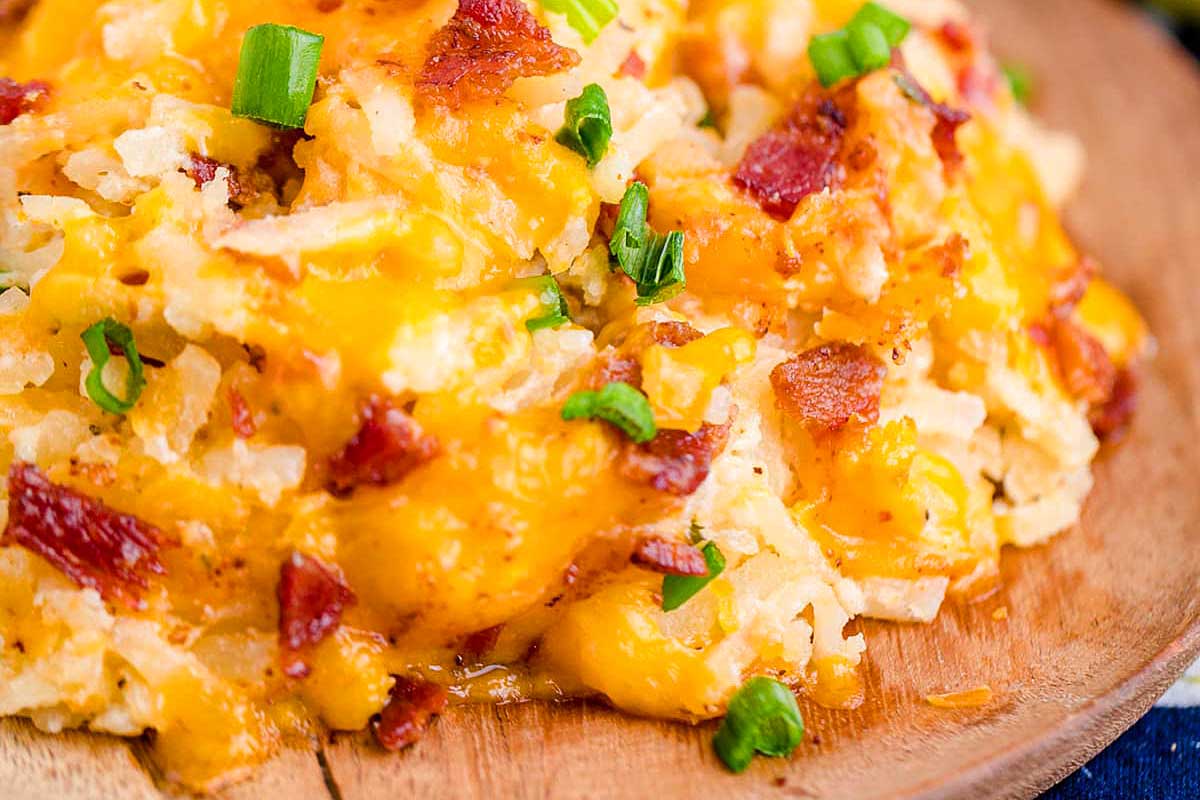 A plate of cheesy Mashed Potato casserole with bacon and green onions.