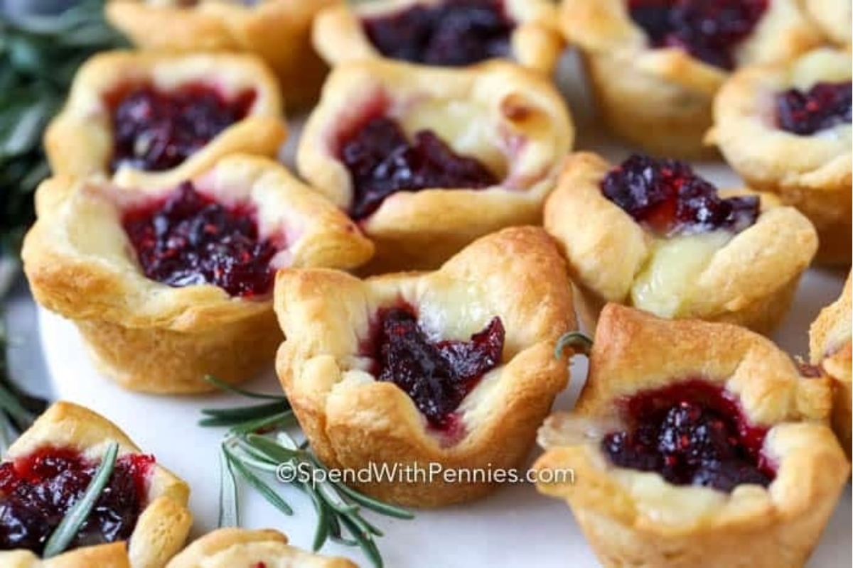 Mini cranberry tarts garnished with rosemary sprigs on a white plate.