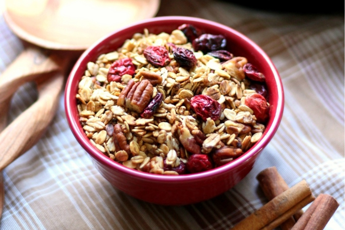 Cranberry granola in a red bowl with cinnamon sticks, perfect for gifting.