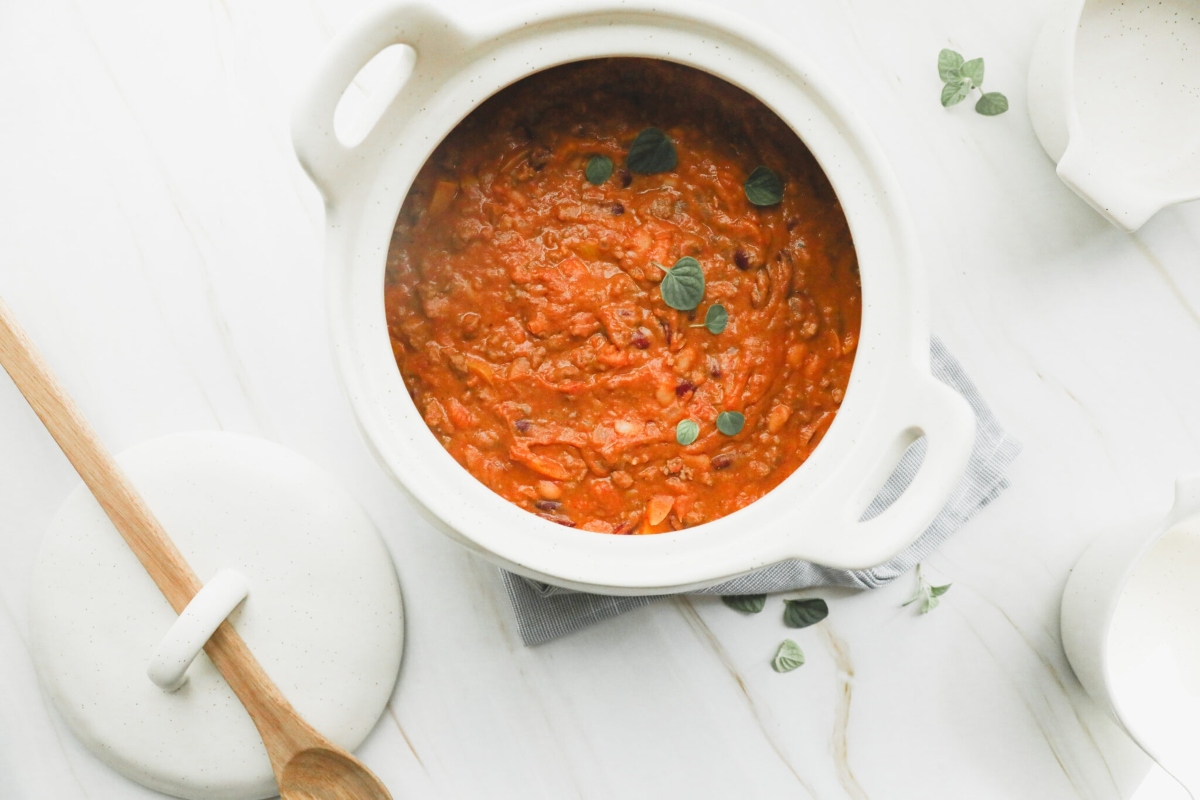 A white bowl containing a delectable red sauce sits elegantly on a clean and pristine white table.