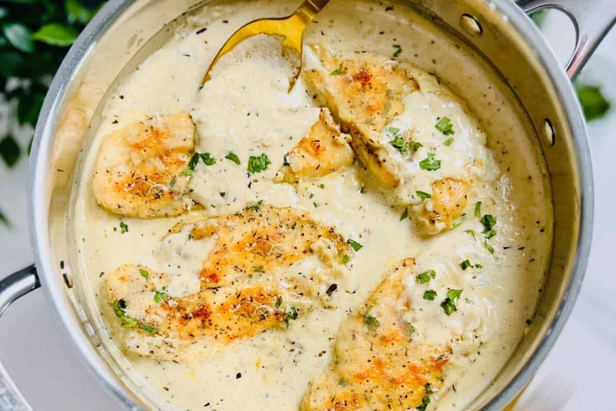 A creamy chicken breast recipe drizzled with truffle oil, served with a spoon.