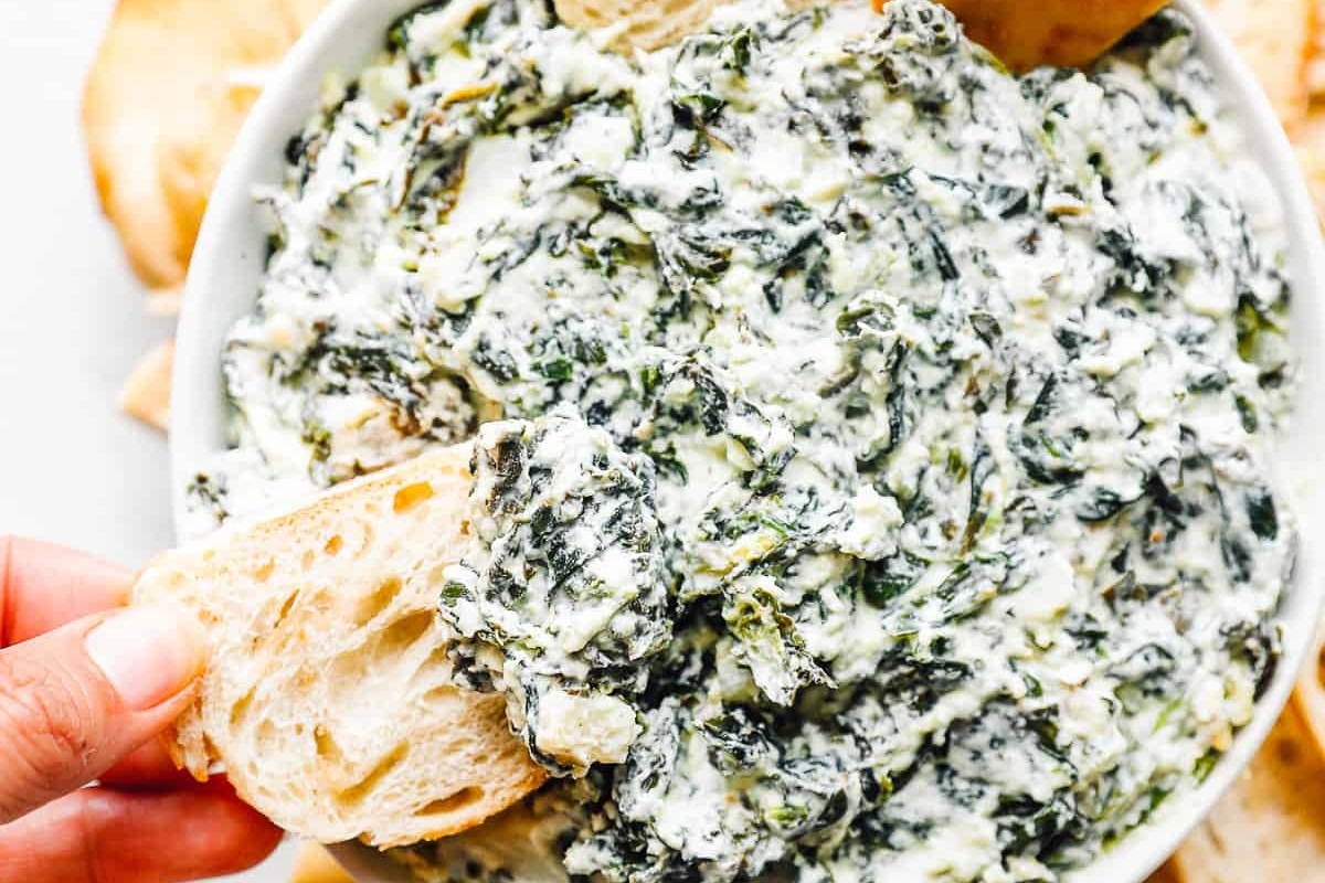 This recipe features a delicious spinach dip served in a white bowl, perfect for pairing with crackers.