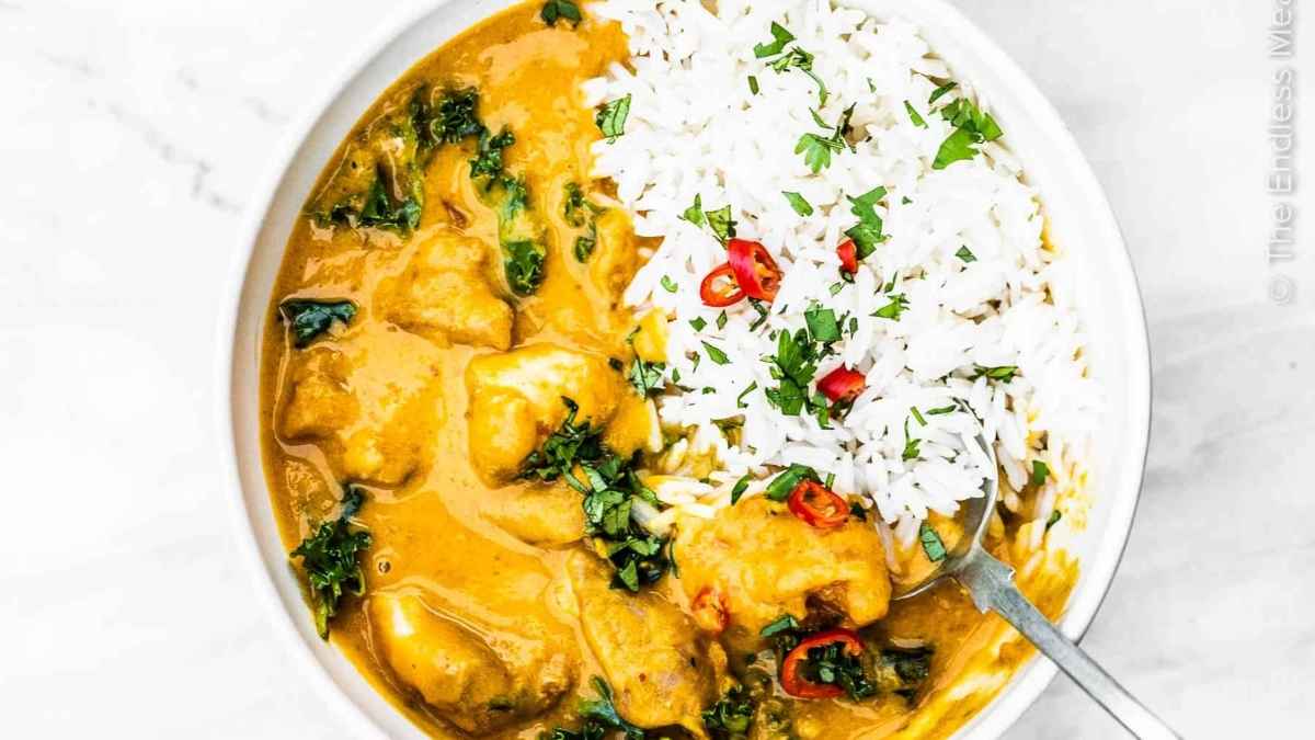 A slow cooker chicken curry with rice and greens.