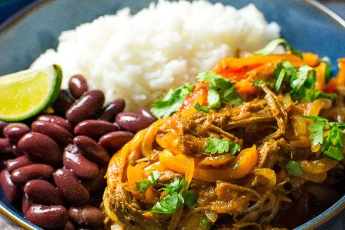 A delectable bowl of Mexican pulled pork stew served with rice and beans.