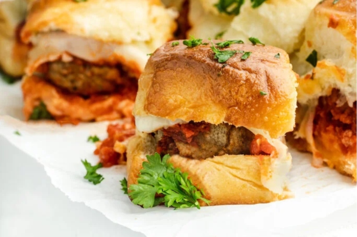Game Day sliders topped with a tangy sauce and fresh parsley.