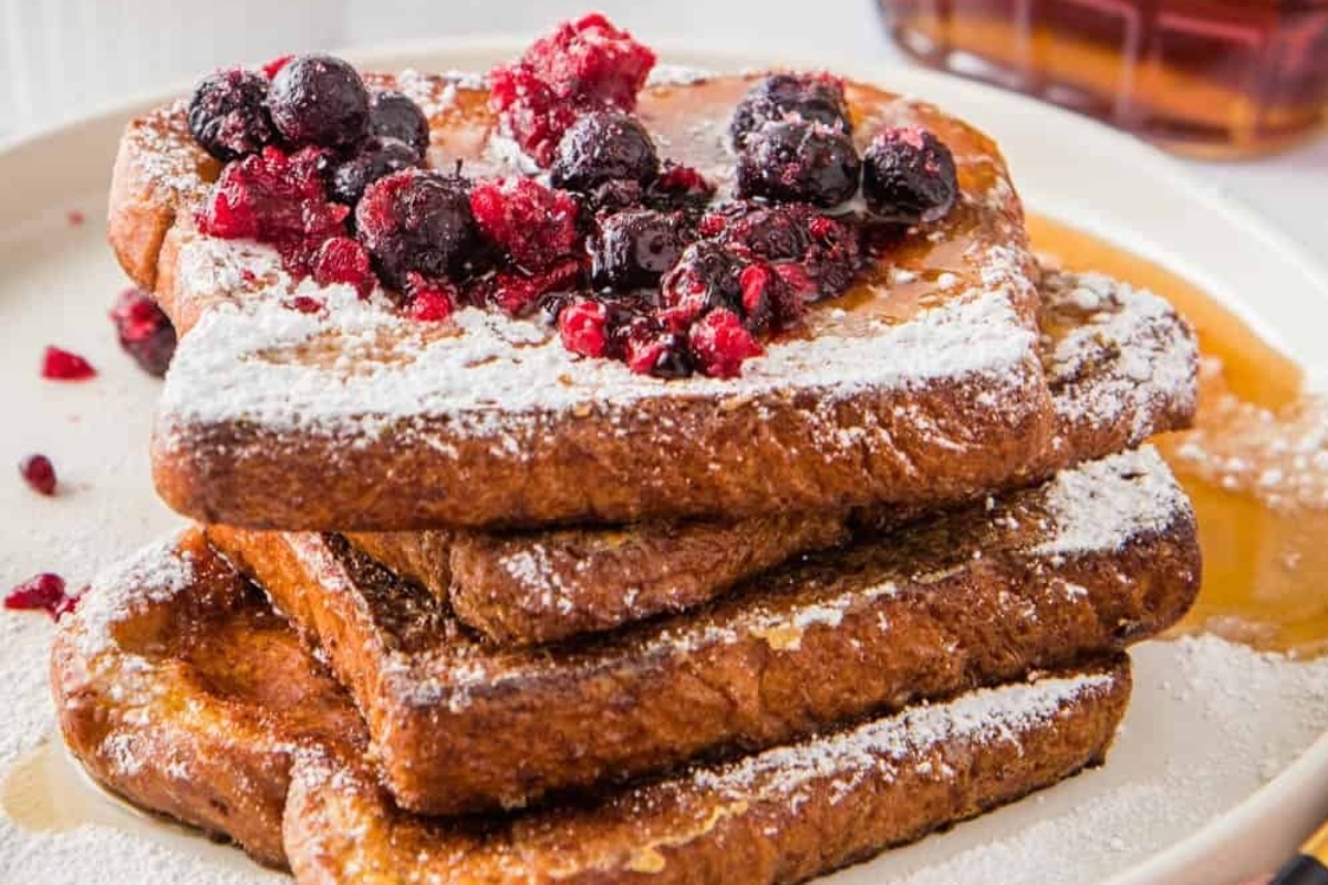 An Easy Breakfast Recipe of a stack of french toast with berries and powdered sugar.