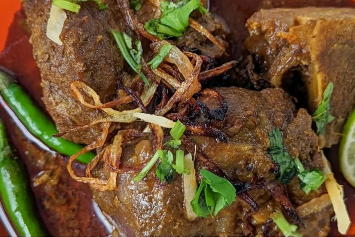 A hearty stew of meat and vegetables served on an orange plate.