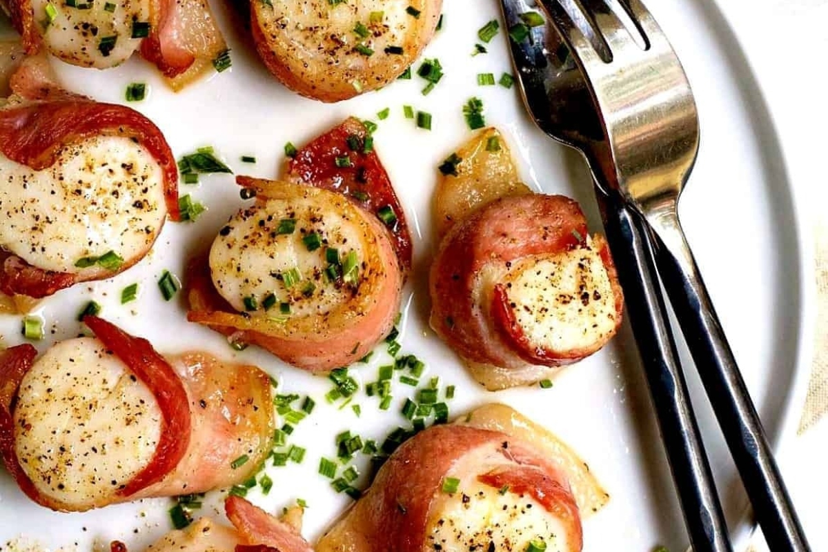 Surf and Turf - Scallops with bacon and chives on a plate.