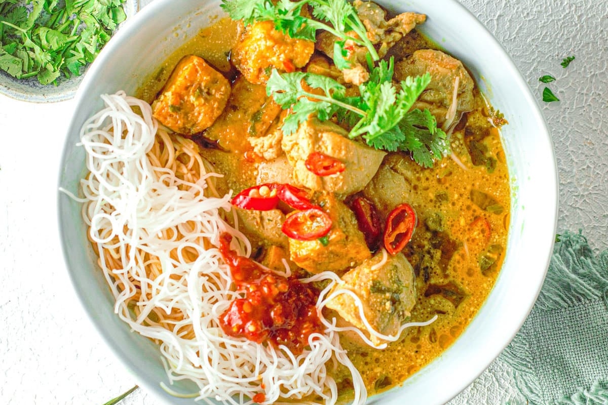 Curry recipe: Thai chicken curry in a white bowl with noodles.