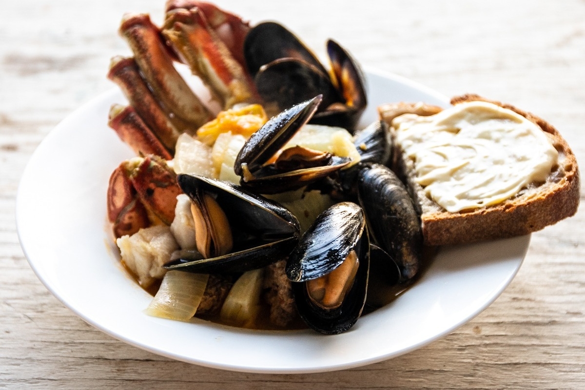 A magnificent feast of the seven fishes spread out on a wooden table, showcasing a bowl of succulent mussels and freshly-baked bread.
