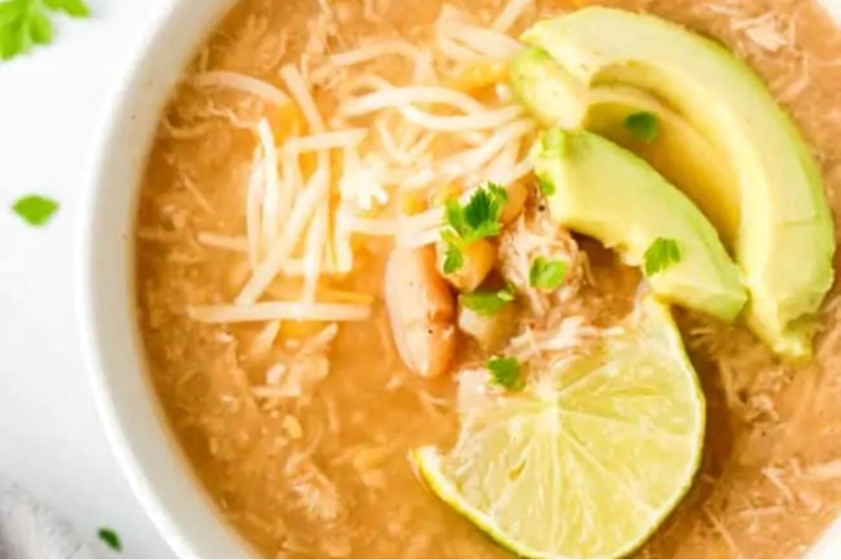 A bowl of Mexican chicken soup with avocado and lime, perfect for those craving a touch of spice in their chili recipes.