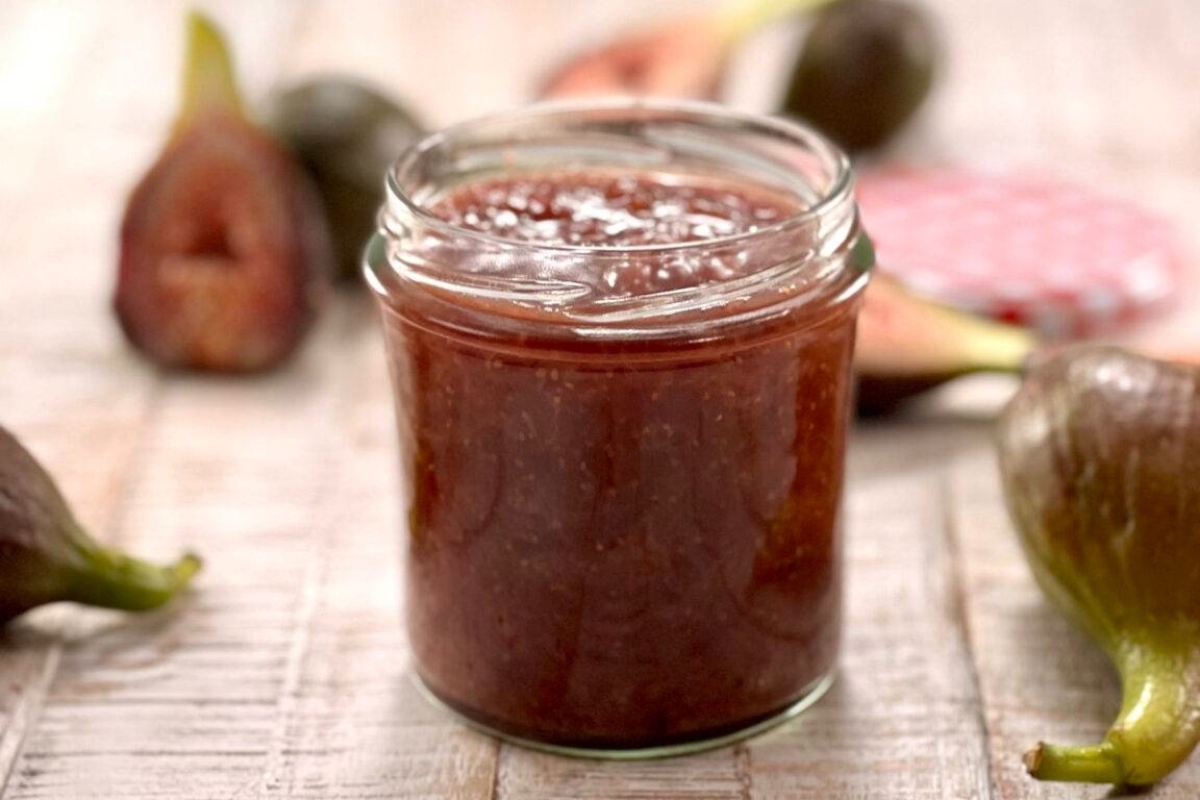 A jar of fig jam displayed on a wooden table, perfect for gifting.