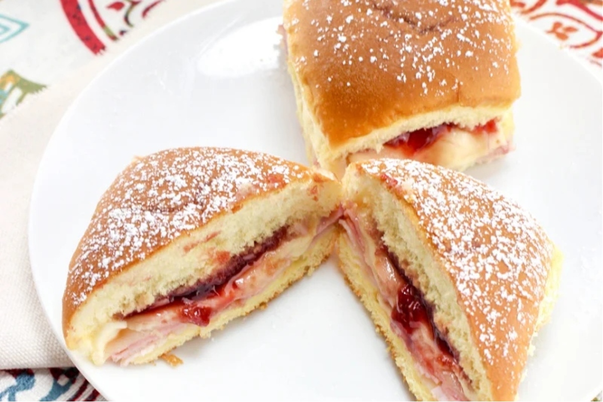 Bite-sized ham and cheese sandwiches with powdered sugar, perfect for game day.