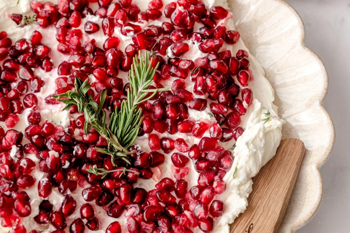 An appetizing pomegranate cheesecake with rosemary sprigs, perfect for indulging in the rich flavors of goat cheese.
