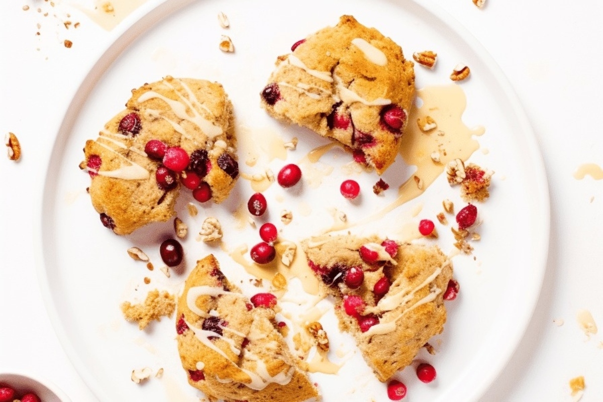 A delicious snack of cranberry scones, adorned with vibrant cranberries and crunchy nuts, presented tastefully on a plate. Enjoy the ultimate cranberry treat!