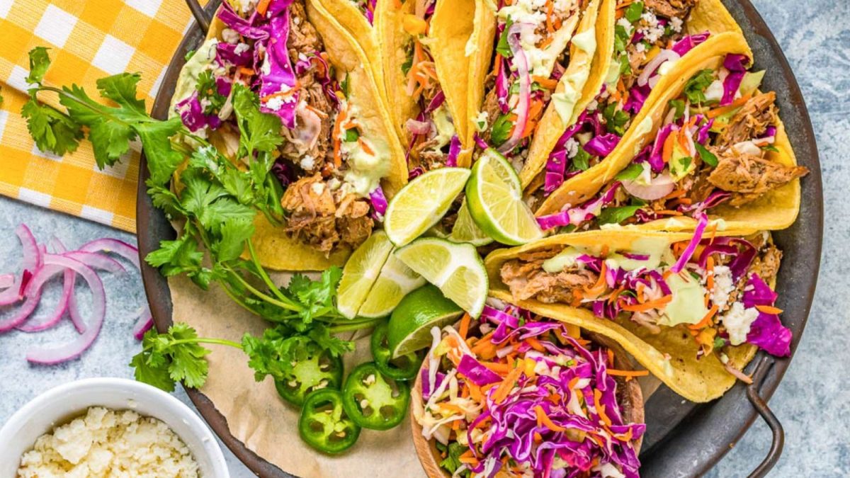 Chicken tacos on a plate with slaw and limes.