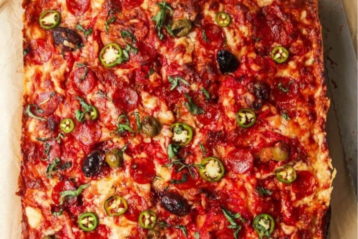 A Focaccia pizza topped with pepperoni and olives on a cutting board.