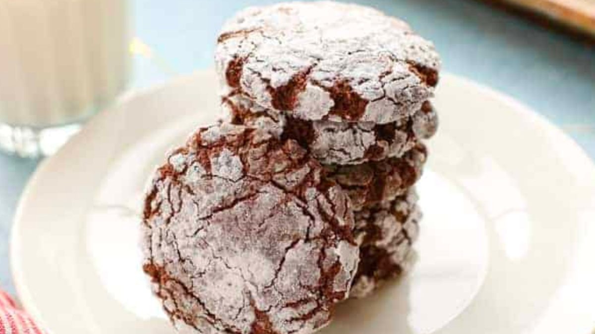 Delicious chocolate crinkle cookies on a plate next to a glass of milk, perfect for Christmas desserts.