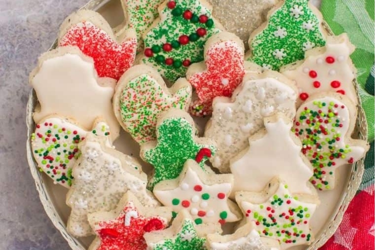 Christmas cut out sugar cookies on a plate with icing and sprinkles.