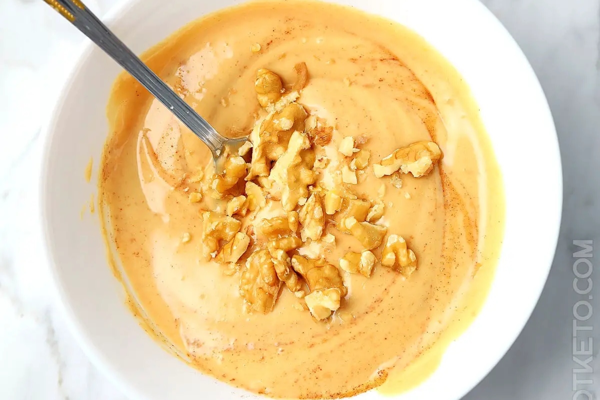 A healthy bowl of pumpkin soup with a spoon in it.