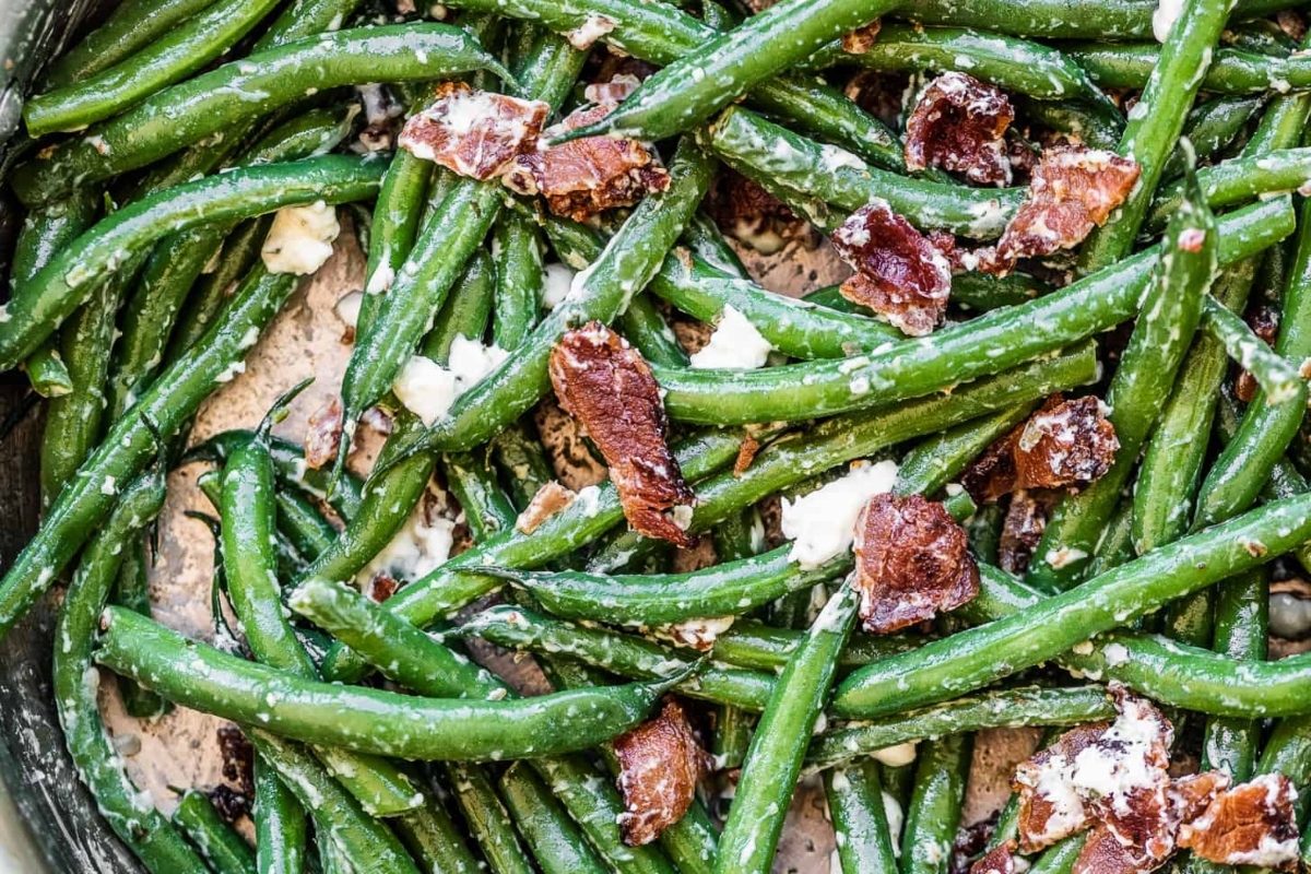 Make-ahead green beans with bacon and cheese in a skillet for Thanksgiving.