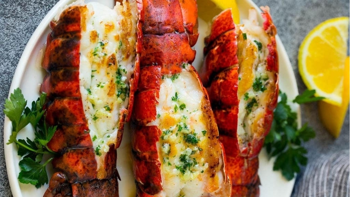 Indulge in a romantic Valentine's Day dinner with three exquisite lobster tails served on a plate garnished with fresh lemon wedges. A perfect choice for a memorable main dish.