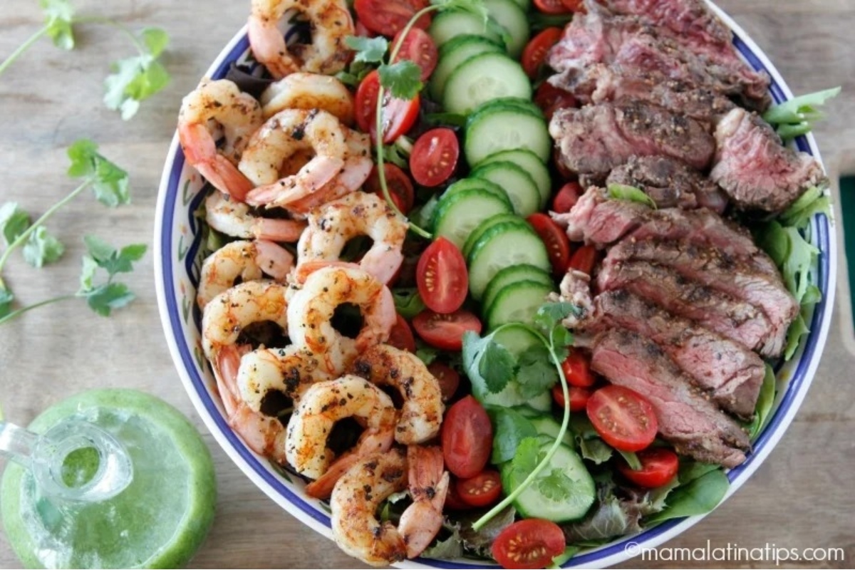 A surf and turf salad with steak, shrimp, tomatoes and cucumbers.