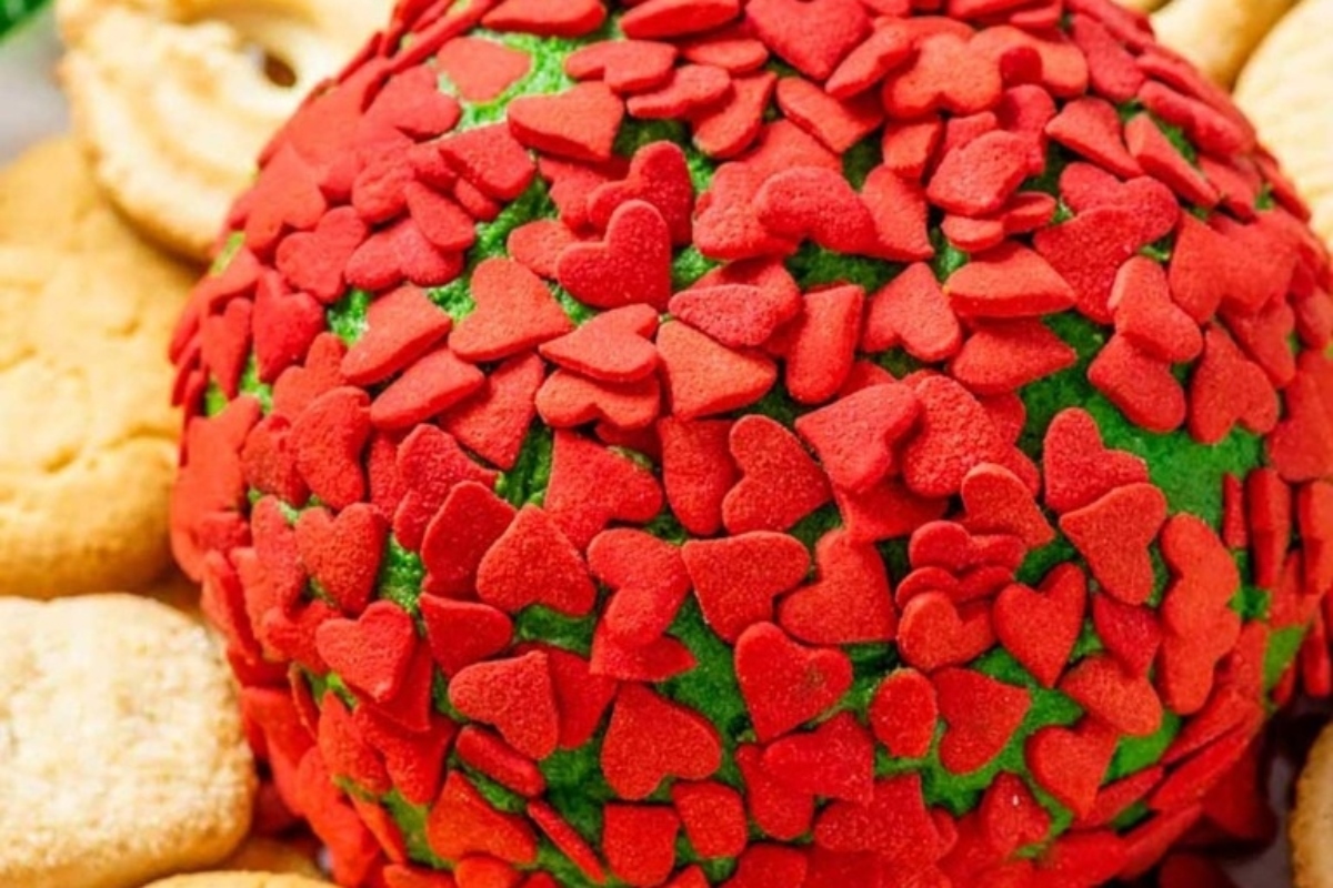A festive cheese ball shaped like a heart, with cookies surrounding it.