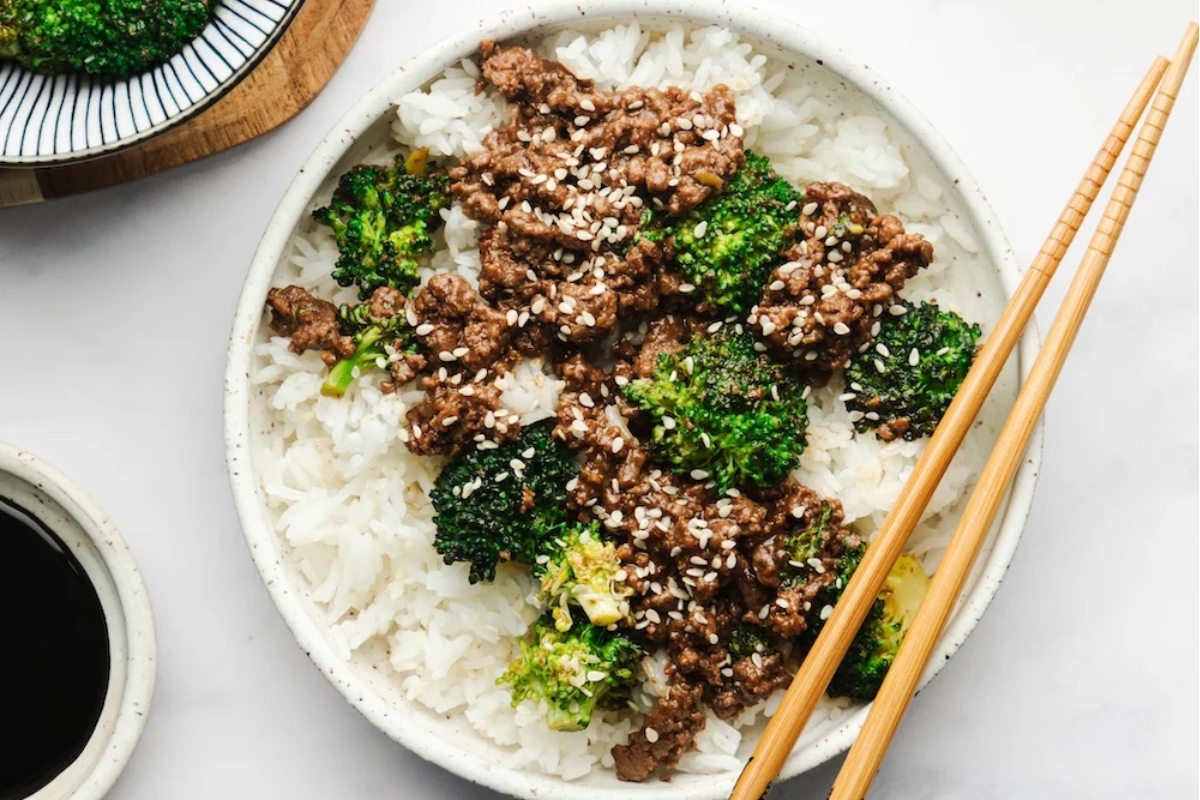 A grain bowl of beef, broccoli and rice with chopsticks.