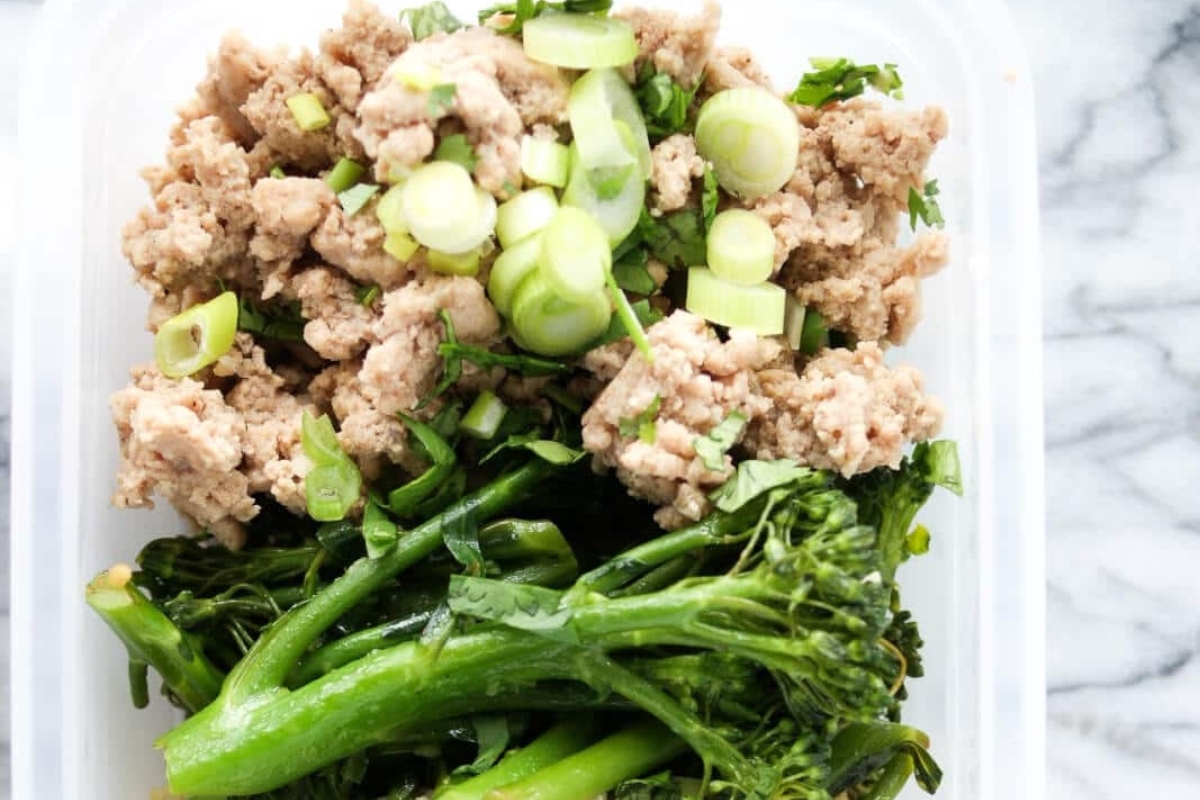 A nutritious grain bowl recipe featuring a plastic container filled with a delicious combination of meat and broccoli.