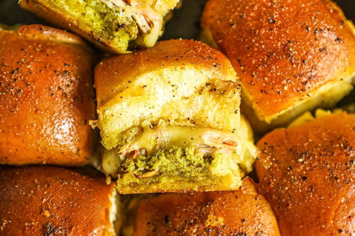 Bite-sized sliders with cheese and pesto, perfect for game day.