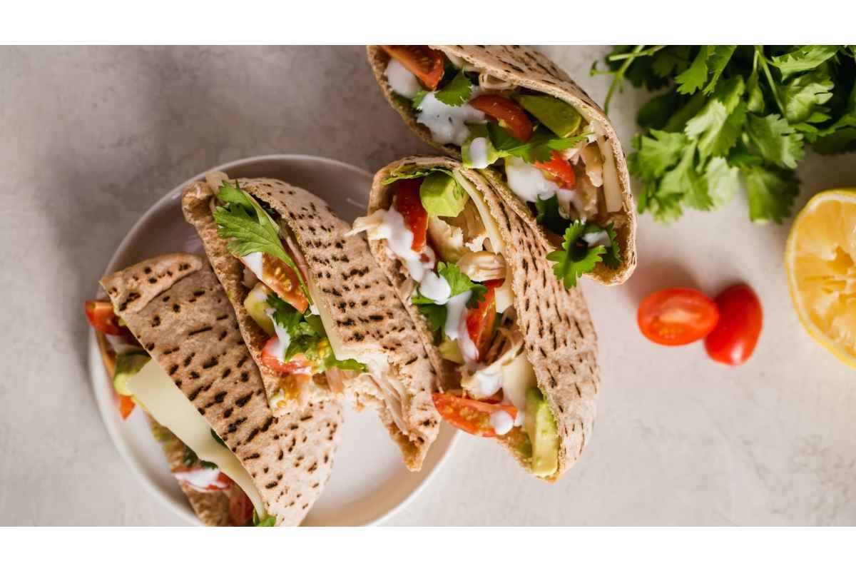 A healthy lunch of pitas filled with tomatoes, lettuce, and lemons offers a high protein option for a satisfying meal.