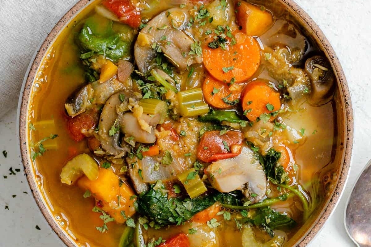 A bowl of vegetable soup with a spoon, slow cooker.