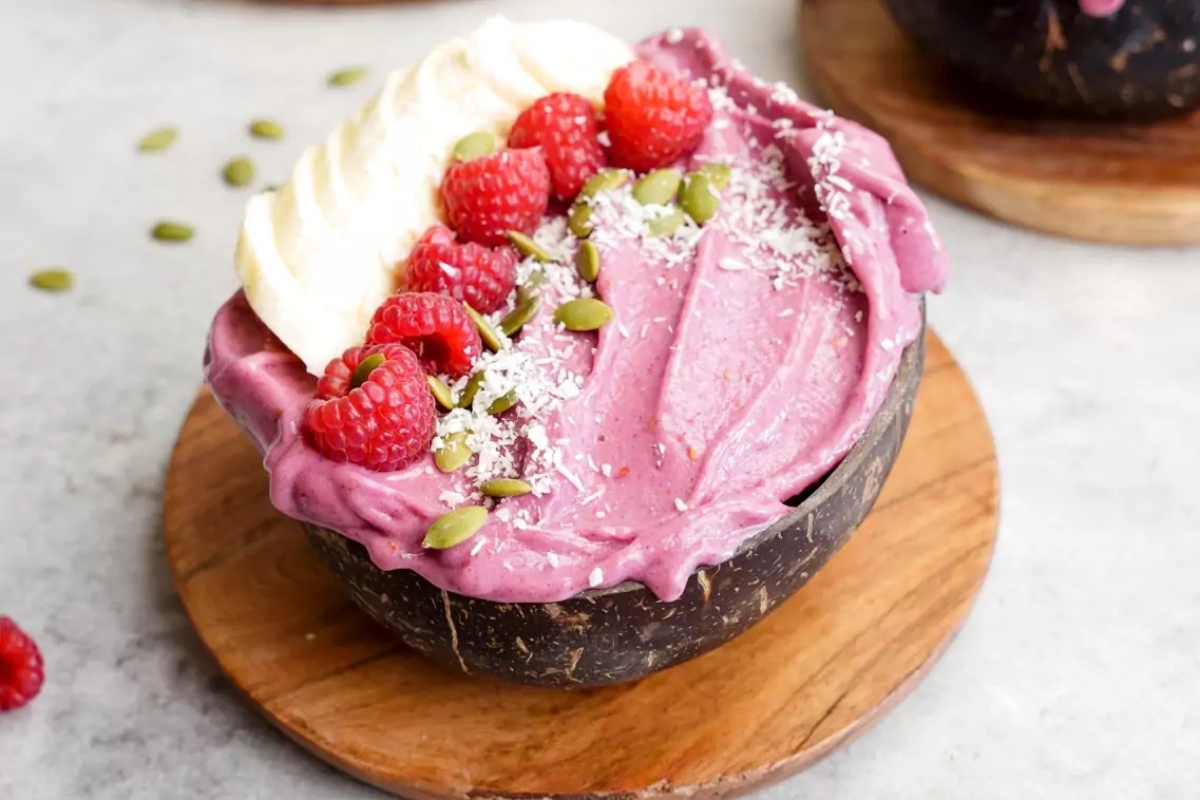 Two healthy breakfast bowls with raspberries and pistachios on top, high in protein.