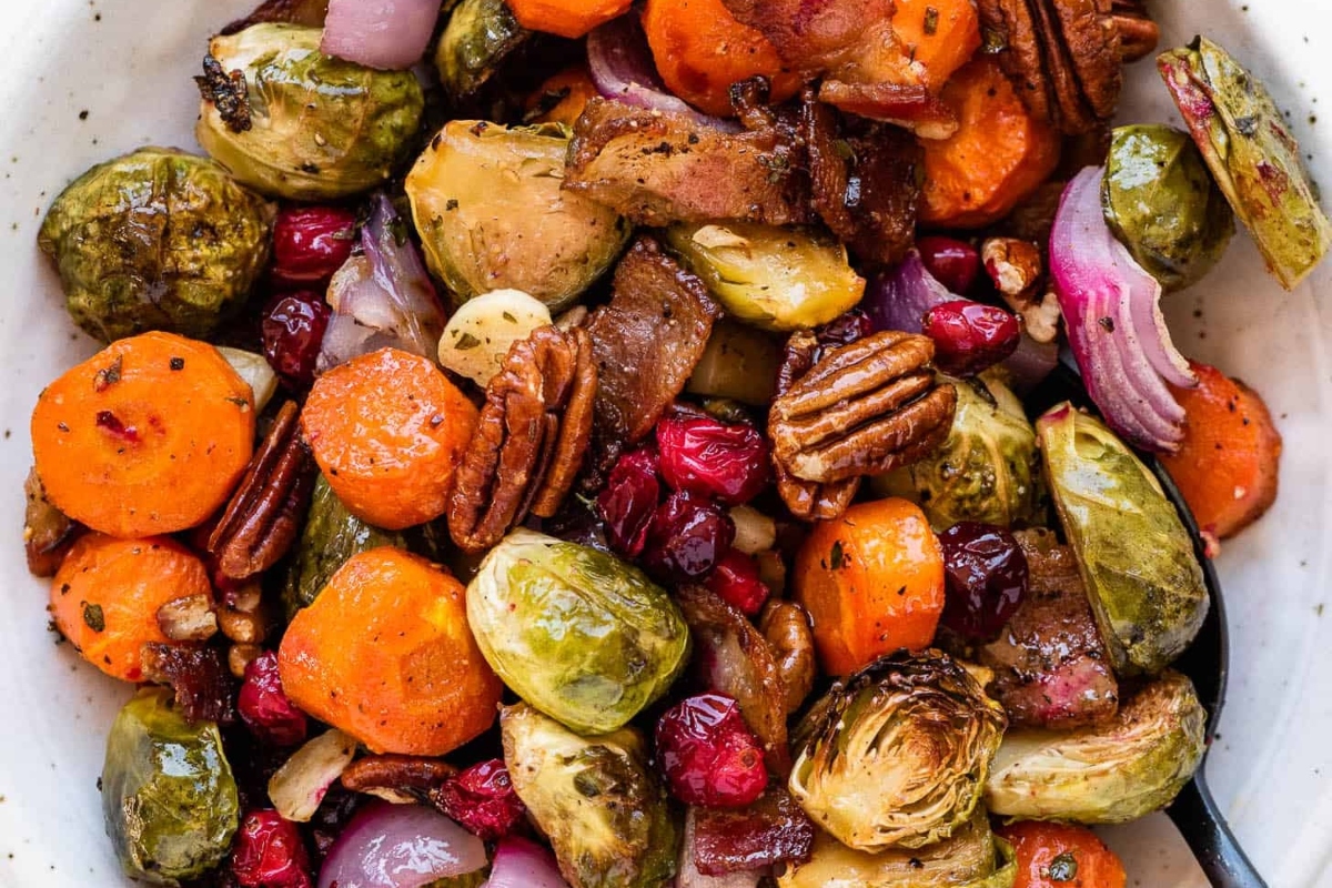 Make-ahead Thanksgiving side dish featuring Brussels sprouts, carrots and cranberries in a white bowl.