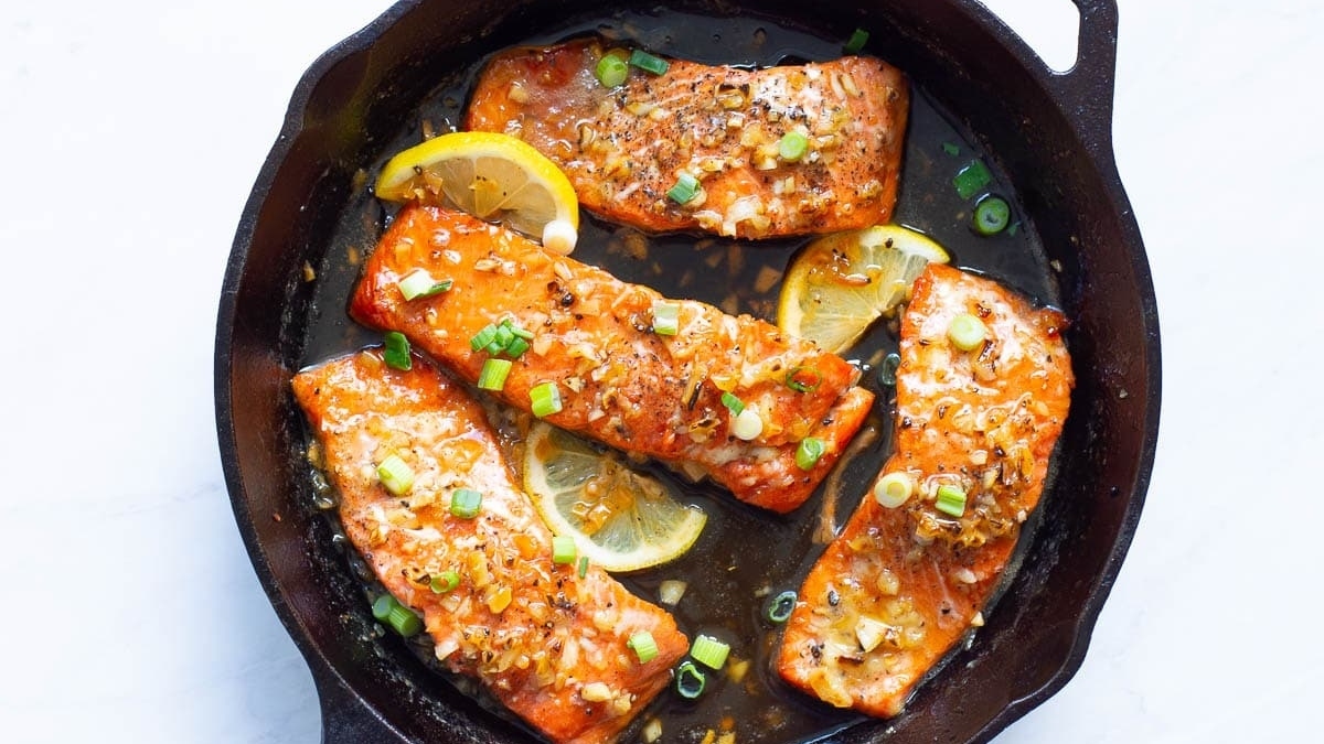 Salmon fillets in a skillet with lemon slices, perfect for a quick and delicious salmon dinner.